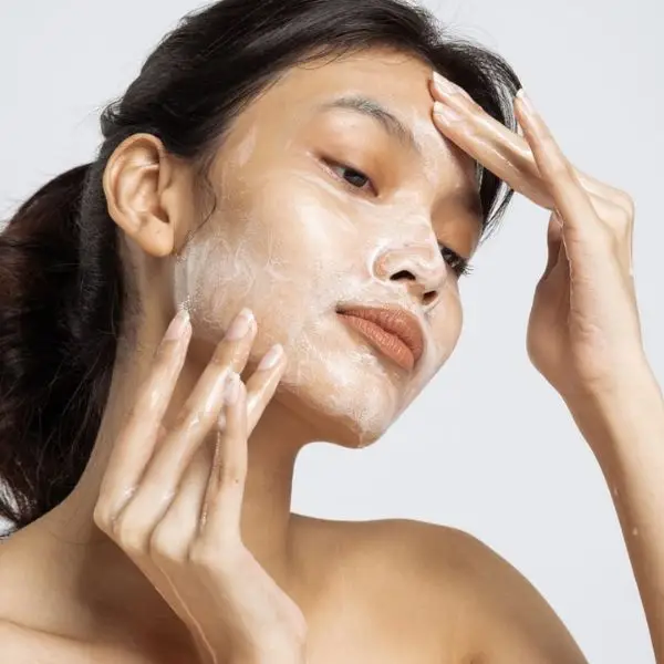 Mulher jovem sorrindo com pele radiante fazendo rotina de skincare para iniciantes.